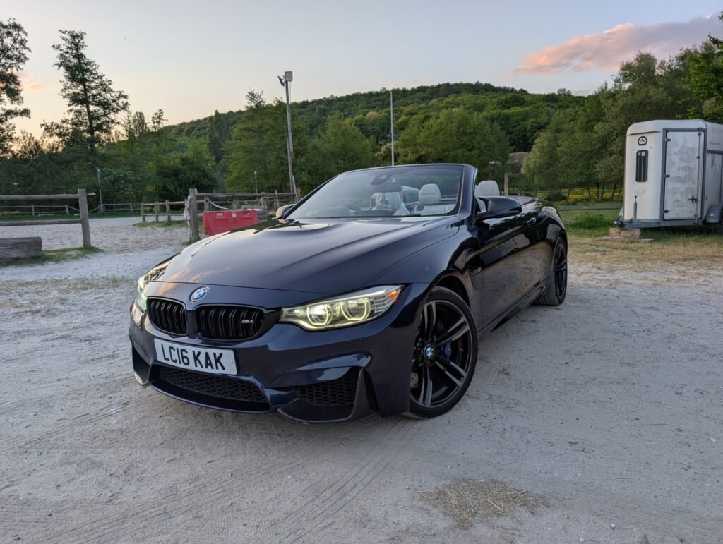 BMW M4 Cabriolet F83 bleu foncé, capote ouverte, immatriculée au Royaume-Uni, photographiée en Angleterre avant son convoyage vers la France